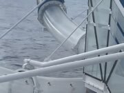 El pasajero del momento doloroso está atrapado en el tobogán del crucero en el agua mientras los pasajeros miran