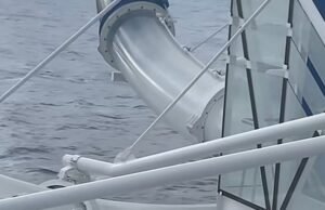 El pasajero del momento doloroso está atrapado en el tobogán del crucero en el agua mientras los pasajeros miran
