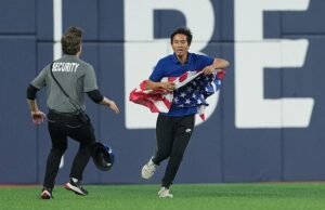 Fanático de la Serie Mundial con bandera estadounidense invade el campo en Toronto antes de ser abordado bruscamente por la seguridad