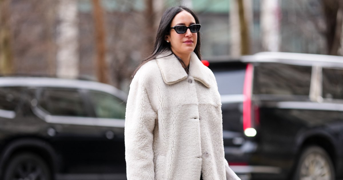 NUEVA YORK, NUEVA YORK - 8 DE FEBRERO: Una invitada usa gafas de sol negras, aretes de diamantes de oro blanco, abrigo de sherpa esponjoso color crema, bolso de mano de cuero Chanel acolchado negro brillante y botas de cuero de tacón negro brillante, en las afueras de Altuzarra durante la Semana de la Moda de Nueva York Otoño / Invierno 2025 el 8 de febrero de 2025 en Nueva York, Nueva York. (Foto de Edward Berthelot/Getty Images)