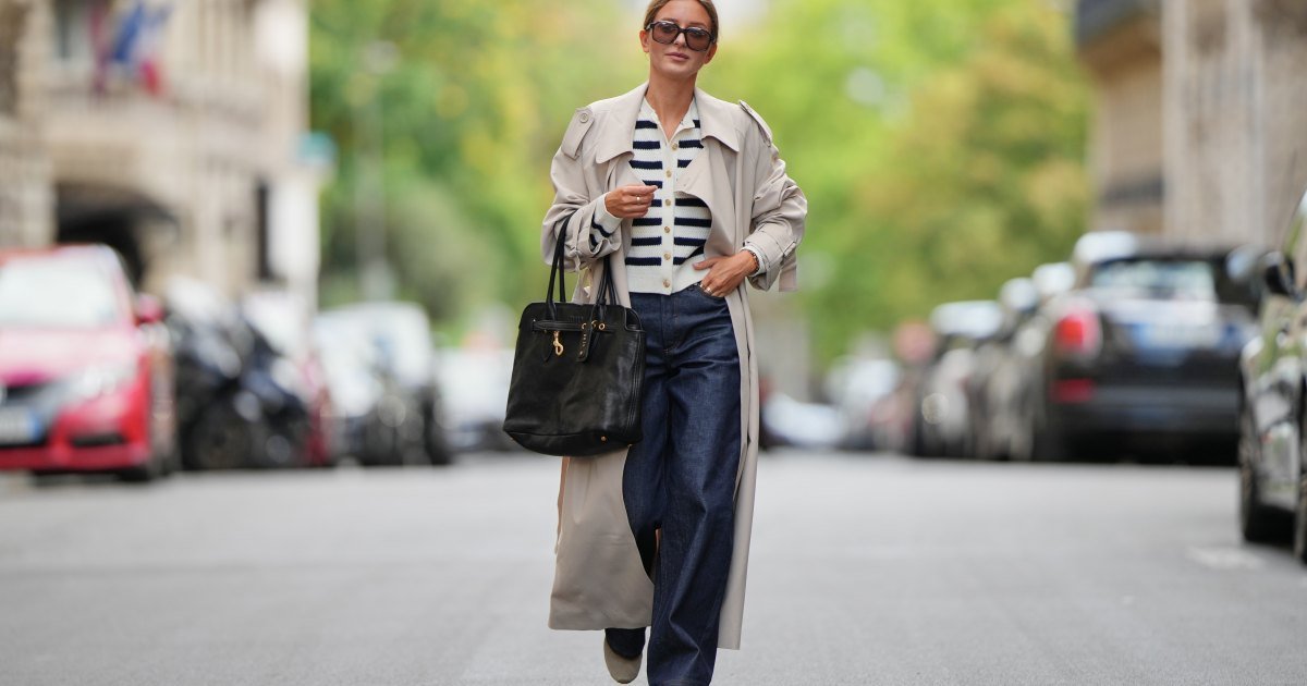 PARÍS, FRANCIA - 5 DE SEPTIEMBRE: Diane Batoukina viste cabello castaño peinado en un elegante moño bajo, gafas de sol oscuras de gran tamaño de Kaleos, gabardina beige de The Frankie Shop, cárdigan abotonado a rayas blancas y azul marino de APC, jeans anchos azul oscuro de APC, bolso de cuero negro Miu Miu con detalles dorados y zapatillas beige y blancas de Miu Miu, durante una sesión de fotos de moda de estilo urbano, el 5 de septiembre de 2025 en París, Francia. (Foto de Edward Berthelot/Getty Images)