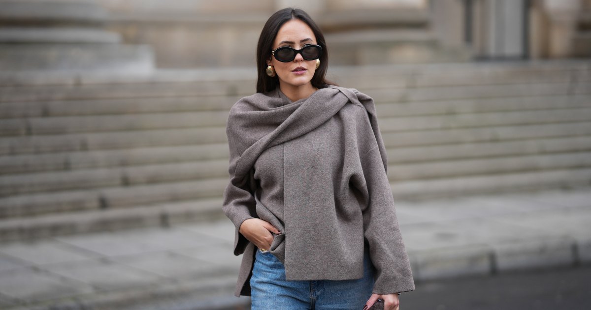 Laura Noltemeyer luce un fino suéter de punto color topo con un escultural cuello drapeado de Zara; jeans rectos en denim azul claro ligeramente descolorido de Zara; botas de invierno de ante beige con punta redondeada, cordones de cuerda, costuras tonales y suela de goma gruesa de Inuikii; un bolso de hombro grande en color marrón oscuro texturizado con una forma escultórica suave y flexible y cuero tejido de Visionnaires x Michi de Want; gafas de sol ovaladas negras con montura de acetato brillante y lentes oscuras de Céline; gruesos aretes esculturales de oro de Zara; guantes de cuero suave marrón oscuro de Zara; su cabello castaño oscuro lo lleva liso con raya en medio, escondido detrás de sus orejas el 25 de noviembre de 2025 en Berlín, Alemania.