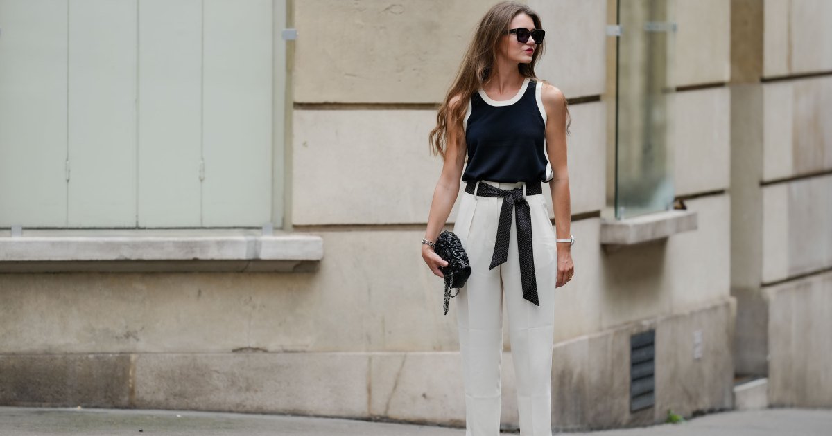 Ségolène Hyppolite usa gafas de sol, lápiz labial/maquillaje, camiseta sin mangas azul marino oscuro/blanco y negro de Tara Jarmon, bolso Chanel negro con texturas/detalles florales, reloj Chanel, cinturón con lazo/bufanda estampada con lunares blancos y negros, pulsera de flores blancas, pantalones cortos blancos de Tara Jarmon, zapatos de tacón blancos/zapatos puntiagudos de Jonak, durante una sesión de fotos de moda urbana, el 12 de mayo de 2024 en París, Francia.