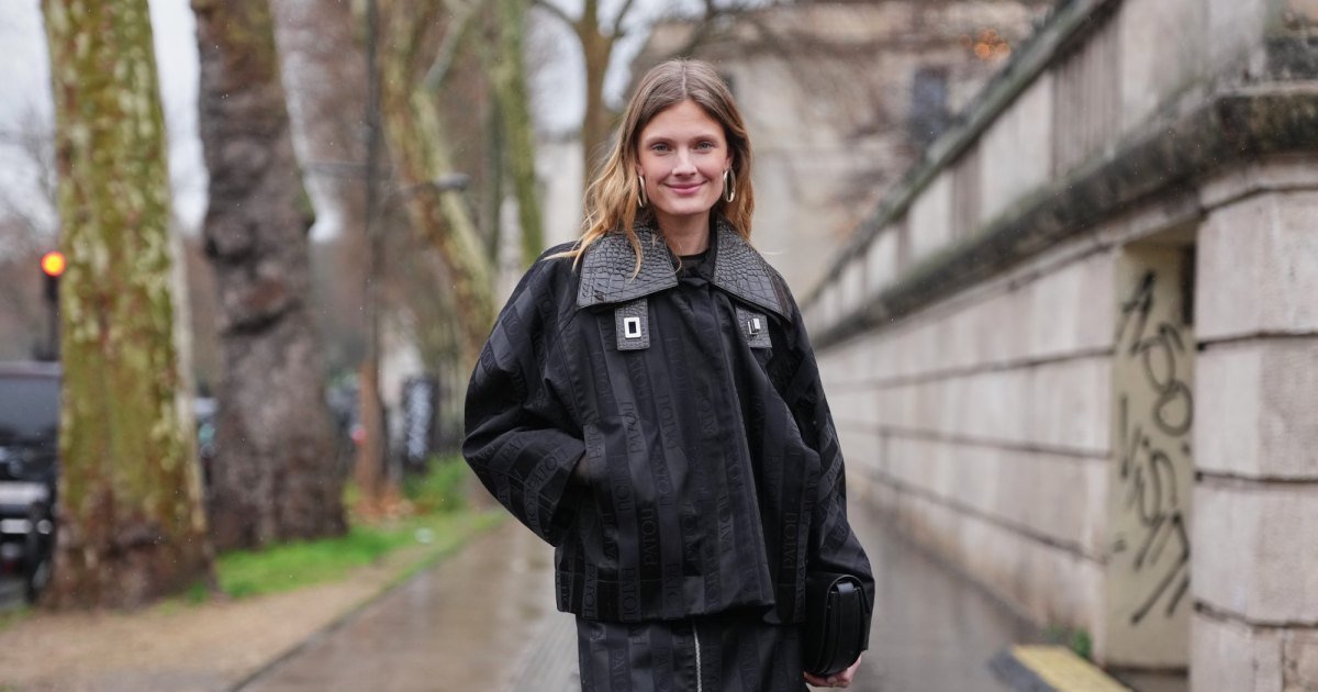 PARÍS, FRANCIA - 25 DE ENERO: Constance Jablonski viste cabello rubio largo y ondulado con raya central, aretes de metal, bolso de mano de cuero negro, chaqueta extragrande negra con rayas de jacquard con el logotipo de PATOU tonal, cuello de cuero texturizado y detalles de hebilla de metal en capas sobre un top negro, minifalda a juego, bota delgada de cuero negro brillante, en las afueras de Patou, durante la Semana de la Moda de París - Moda masculina Otoño/Invierno 2026-2027, el 25 de enero. 2026 en París, Francia (Foto de Edward Berthelot/Getty Images)