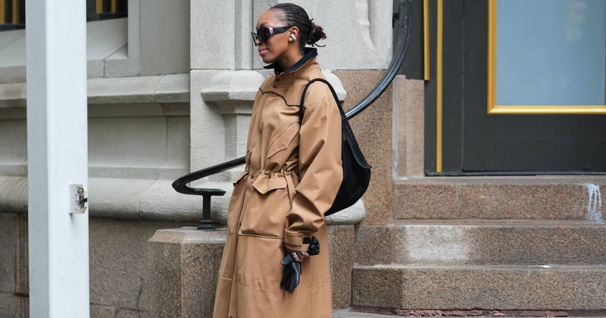 NUEVA YORK, NUEVA YORK - 15 DE FEBRERO: Una invitada lleva el pelo negro recogido en un moño, gafas de sol envolventes negras, auriculares inalámbricos negros, mochila tejida negra, gabardina de algodón beige con cuello alto y guantes de cuero negros, en las afueras de Diotima durante la Semana de la Moda de Nueva York el 15 de febrero de 2026 en la ciudad de Nueva York (Foto de Edward Berthelot/Getty Images)