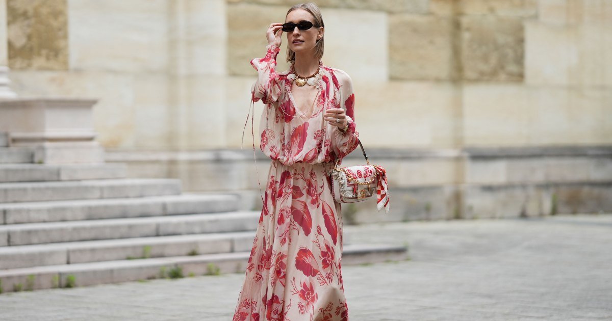 MÚNICH, ALEMANIA - 29 DE MAYO: Marlies Pia Pfeifhofer lleva un vestido largo de gasa beige claro de manga larga con estampados de plumas y flores en rojo y rosa, cintura con cordón, escote en V profundo con lazo en la parte delantera y detalles fruncidos en el cuello y los puños de FENDI, un bolso Baguette de lona de color natural con bordado de bandana en color coral, pequeños flecos en la solapa, correas de piel de becerro, detalles dorados y un logotipo, así como un charm adicional de cadena dorada con colgantes de inspiración marina y un charm de bandana rojo, rosa y blanco con clip con logo dorado de FENDI, un par de sandalias de gladiador de cuero marrón chocolate con correa de cuero trenzada en la puntera y correa principal de Alex Rivière x Manebi, gafas de sol Louis Tortoise Brown de forma delgada y ovalada de Corlin, un collar Forever Fendi en metal dorado y cuero de napa marrón con colgantes en forma de concha de FENDI, un reloj Tank Louis en cuero marrón con caja rectangular de oro amarillo de FENDI. Cartier, un anillo de plata y diamantes el 29 de mayo de 2025 en Munich, Alemania. (Foto de Moritz Scholz/Getty Images)